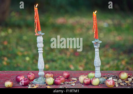 A pair of two candles are lit on a bench of apples. Stock Photo