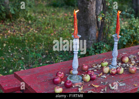 Twin candles burn on a table of apples. Stock Photo
