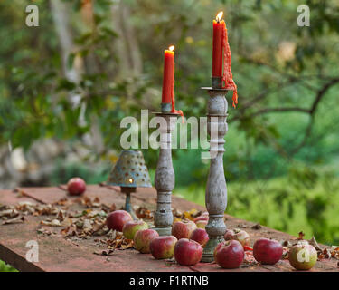 Two candles burn on a table of apples. Stock Photo