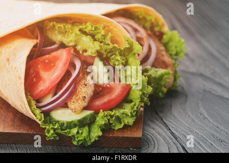 pair of fresh juicy tortilla wraps with chicken and vegetables on table Stock Photo