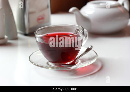 Transparent glass cup of hot red fruit tea on the table. Stock Photo