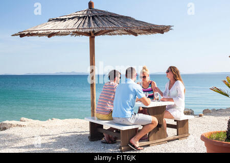 Group of friends sitting at table in beach bar Stock Photo