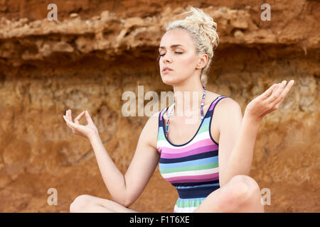 Young woman doing yoga on beach Stock Photo