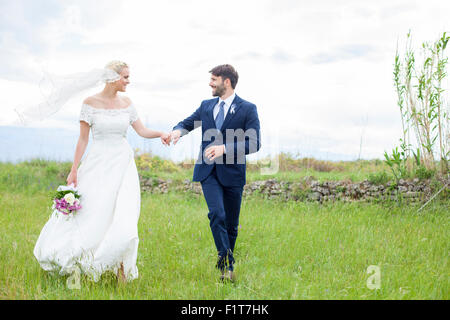 Bride and groom holding hands in the meadow Stock Photo