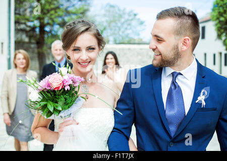 Bride and groom walking with family in background Stock Photo