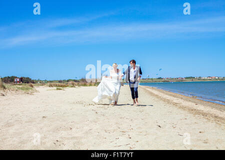 Bride and bridegroom running on beach Stock Photo