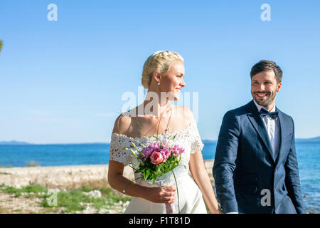 Bride and groom holding hands on beach Stock Photo