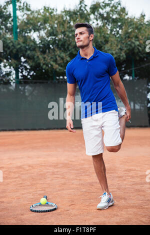 Portrait of a male tennis player stretching leg outdoors Stock Photo