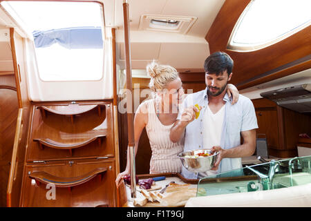 Young couple cooking together in galley of yacht, Adriatic Sea Stock Photo