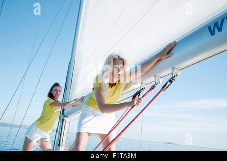 Two women adjusting rigging together on sailboat, Adriatic Sea Stock Photo