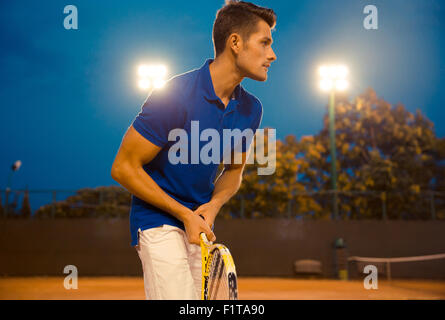 Portrait of a handsome man playing in tennis outdoors at the night Stock Photo