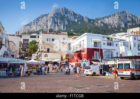 Capri, Italy - August 14, 2015: Port of Capri island, tourists, cars, building facades with rocky mountains on a background Stock Photo