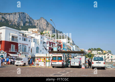 Capri, Italy - August 14, 2015: Cityscape photo of Capri port, tourists, cars, building facades with rocky mountains on a backgr Stock Photo