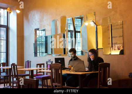 Young man and young woman working on computers in a Porto cafe. Stock Photo