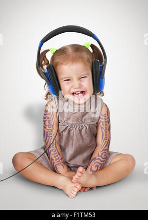 Funny child girl with tatoo listening music in headphones Stock Photo