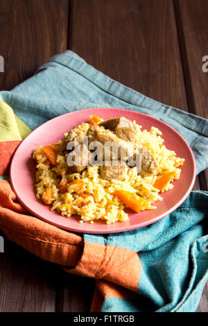 Rice pilaf with lamb meat and vegetables on wooden table and napkin close up Stock Photo