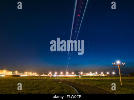 Traces from landing airplanes are illuminating the dark sky above the touch-down point of runway 28 of Zurich Kloten airport. Stock Photo