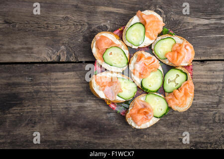 Homemade sandwiches with pink salmon and cucumber. Plate of snack on wooden background with copy space. Top view image menu back Stock Photo