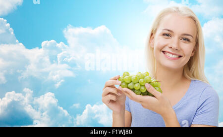 happy woman eating grapes over sky Stock Photo