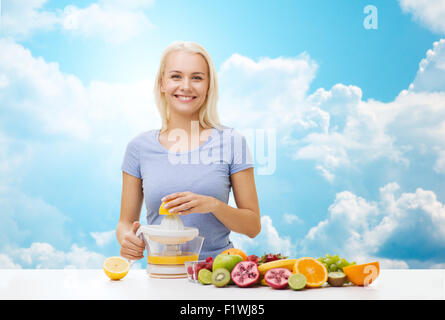 smiling woman squeezing fruit juice over sky Stock Photo