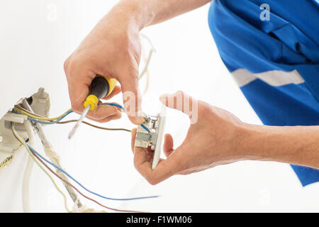 close up of hands with screwdriver fixing socket Stock Photo
