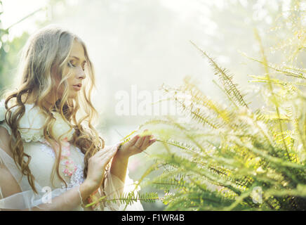 Pretty blonde woman with the green fern Stock Photo