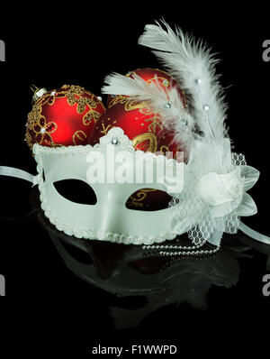 White mask and Christmas red balls on a black background. Stock Photo