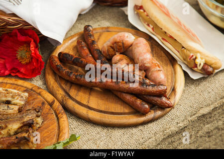 smoked sausages on the wooden plate. Stock Photo