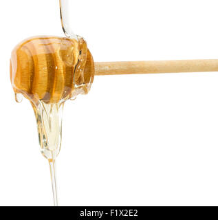 Honey dripping from a wooden spoon on white background. Stock Photo