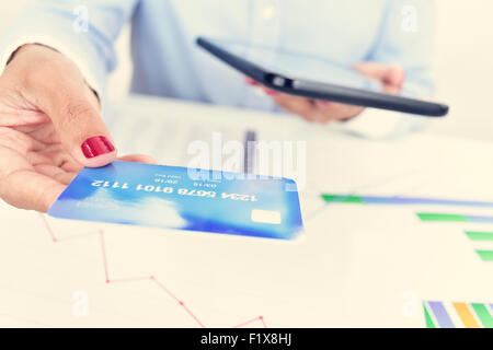 closeup of a young woman at her office with a credit card in one hand and a tablet computer in the other hand Stock Photo