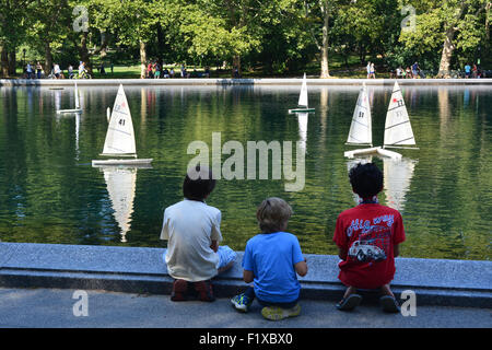 Kids sailing model boats on Water Conservatory in Central Park in New York City. Stock Photo