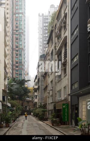 Road worker walking between high rise apartments in Hong Kong's Mid levels Stock Photo