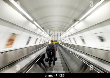 Woman with backpack riding down escalator at the Malostranska metro station in Prague, Czech Republic Stock Photo