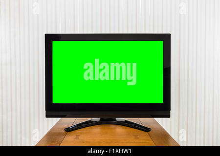 Modern television on wood table with green chroma key screen. Stock Photo