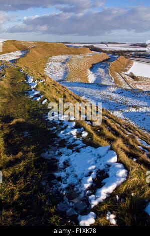Snow partially covers the iron age earth workings of Maiden Castle near Dorchester in Dorset, England, UK Stock Photo