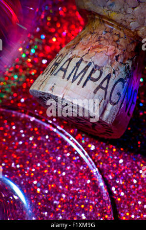 Close up on Champagne cork and glass on sparkling party table surface with multicolor lighting Stock Photo