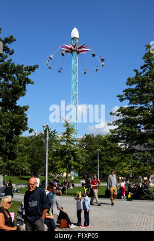 People enjoying the Starflyer fairground ride being used outside the Shell Building on Londons Southbank on a warm summer day Stock Photo