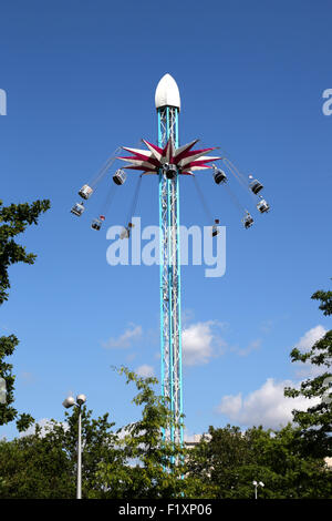 People enjoying the Starflyer fairground ride being used outside the Shell Building on Londons Southbank on a warm summer day Stock Photo