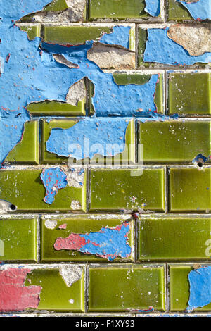 Blue and red paint peeling off green ceramic wall tiles Stock Photo