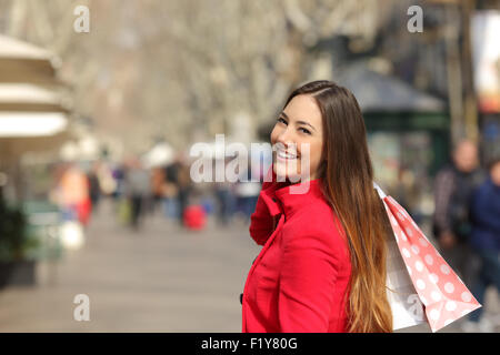 Happy shopper woman walking and shopping in the street in winter holding bags Stock Photo