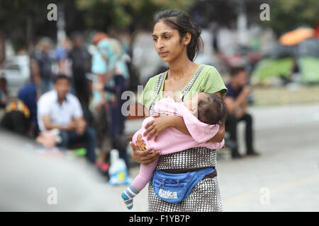 A Syrian woman holding a child in a park full of refugees waiting for the transport to the European Union in Belgrade, Serbia. Stock Photo