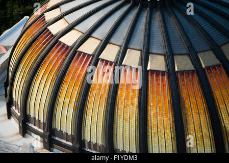 Palacio de Bellas Artes Dome Ceramic Tile Detail Mexico City | MEXICO CITY, Mexico — Glazed ceramic tiles in roughly six graded gold-to-orange tones clad the ribbed dome of the Palacio de Bellas Artes, photographed close-up from the Torre Latinoamericana. Copper-sheathed structural ribs divide each mosaic panel of the dome, which sits atop a metal armature fabricated in Florence, Italy, part of the building's Art Nouveau program completed in 1934. Stock Photo