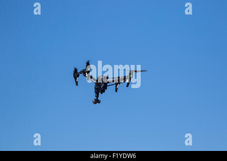 Drone flying against a vivid blue sky Stock Photo