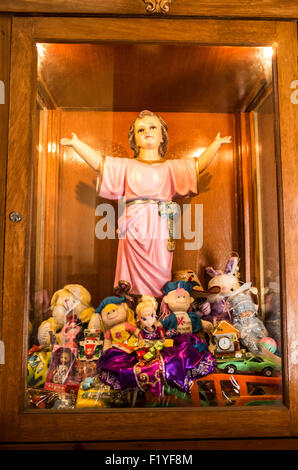 MEXICO CITY, Mexico — A statue dedicated to children in a case packed with toys that have been donated in the Iglesia de la Santisima Trinidad in Mexico City, Mexico. Iglesia de la Santisima Trinidad translates as Church of the Holy Trinity. This colonial-era church continues to serve as a center for religious and cultural activities in the bustling metropolis. Stock Photo