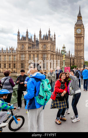 Young Tourists Pose For Selfies In Front Of Big Ben and The Houses Of Parliament, Westminster Bridge, London, England Stock Photo