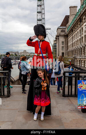A Man Dressed In A Guards Uniform Hands Out Leaflets and Poses For Photographs With Tourists, London, England Stock Photo