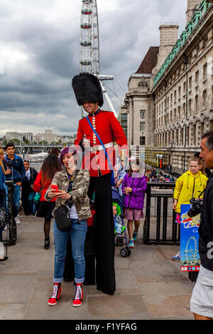 A Man Dressed In A Guards Uniform Hands Out Leaflets and Poses For Photographs With Tourists, London, England Stock Photo