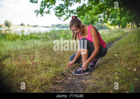 woman girl running around playing sports outdoors tying shoelace Stock Photo