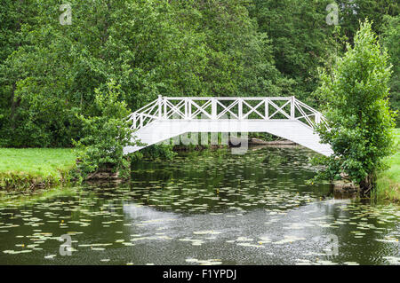 Decorative white wooden bridge over small pond in park Stock Photo