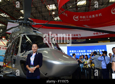 Tianjin, China. 9th Sep, 2015. An exhibitor poses for a photo in front of a helicopter at the Tianjin International Helicopter Exhibition in a helicopter base of Aviation Industry Corporation of China in the Airport Area of China Pilot Free Trade Zone of Tianjin, north China, north China, Sept. 9, 2015. The exhibition displayed 56 helicopters and attracted 366 enterprises. Credit:  Zhang Chenlin/Xinhua/Alamy Live News Stock Photo